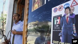 Libya -- A Libyan rebel stands by a shop window decorated with a portrait of Moammar Gadhafi with his son Seif al-Islam on his shoulders, in Tripoli, 25Aug2011